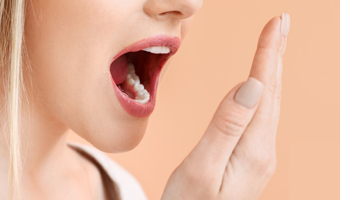 A woman checking her breath by covering her hand near her mouth, focusing on fresh breath concerns.